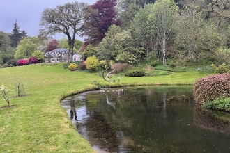 A shot of a wildlife pond with the farmhouse in the background