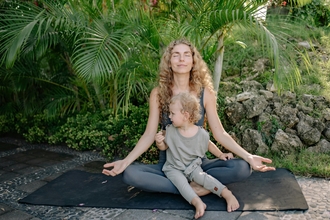 A woman and her small child practising yoga outside
