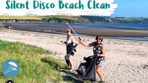 Two people litter picking on a beach with headphones on