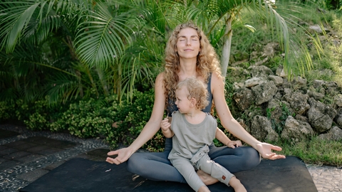 A woman and her small child practising yoga outside