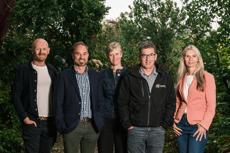 Image of five people with a background of trees